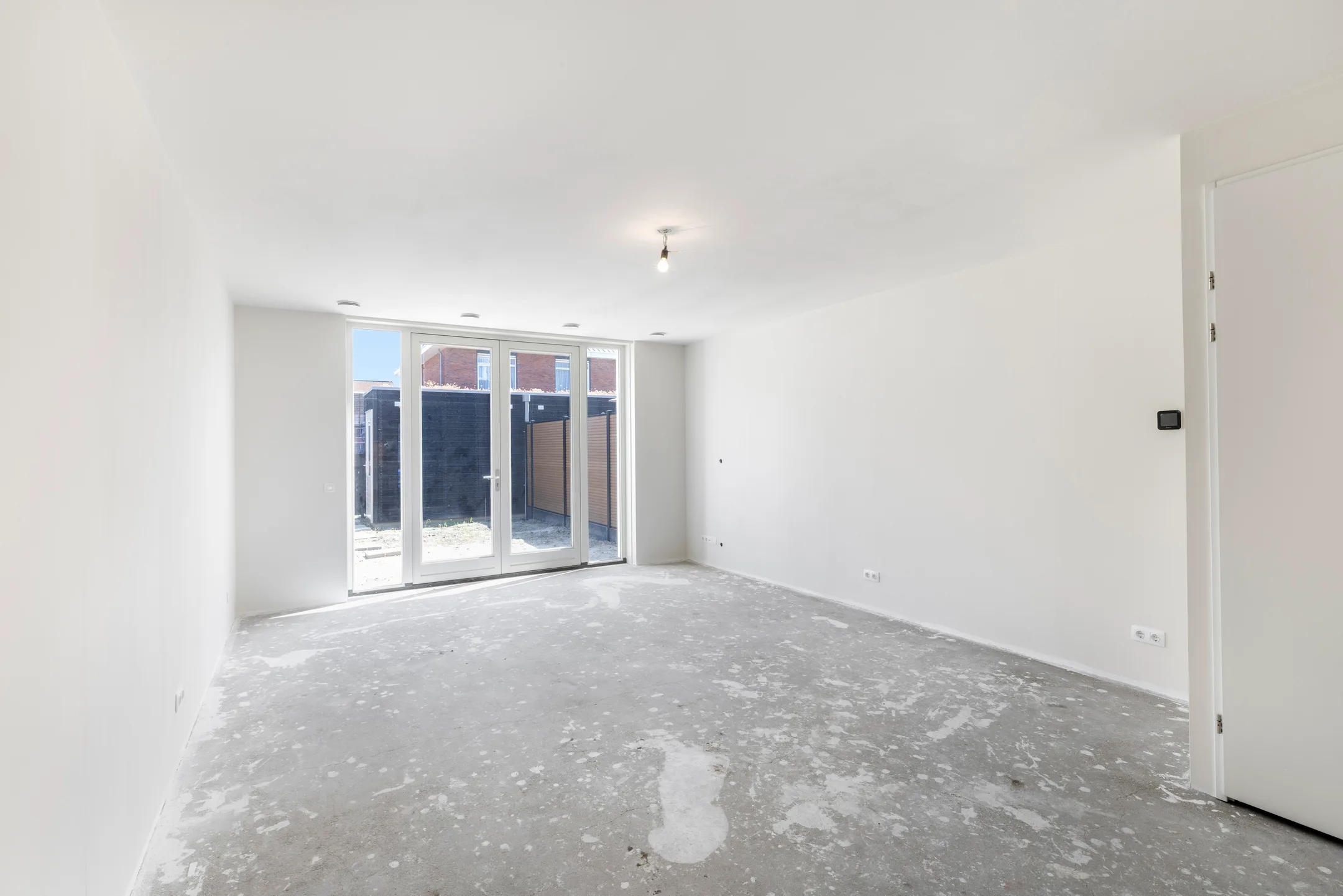 Lege woonkamer met tuindeuren in een net opgeleverde woning