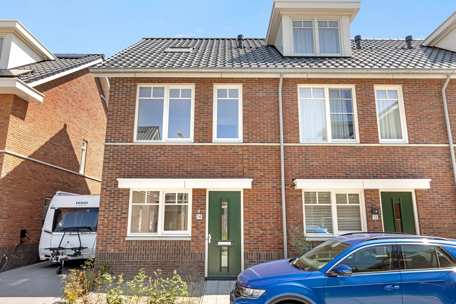 Voorgevel van de nieuwbouwwoning met een groene voordeur