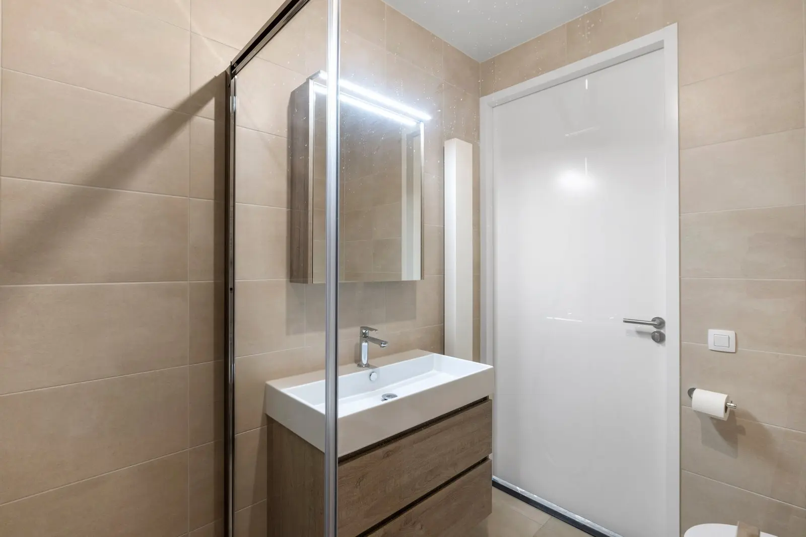 Badkamer met wastafelmeubel en verlichte spiegel