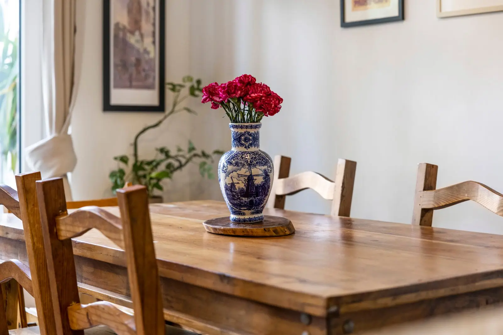 Detail van de houten tafel met de vaas met rode bloemen