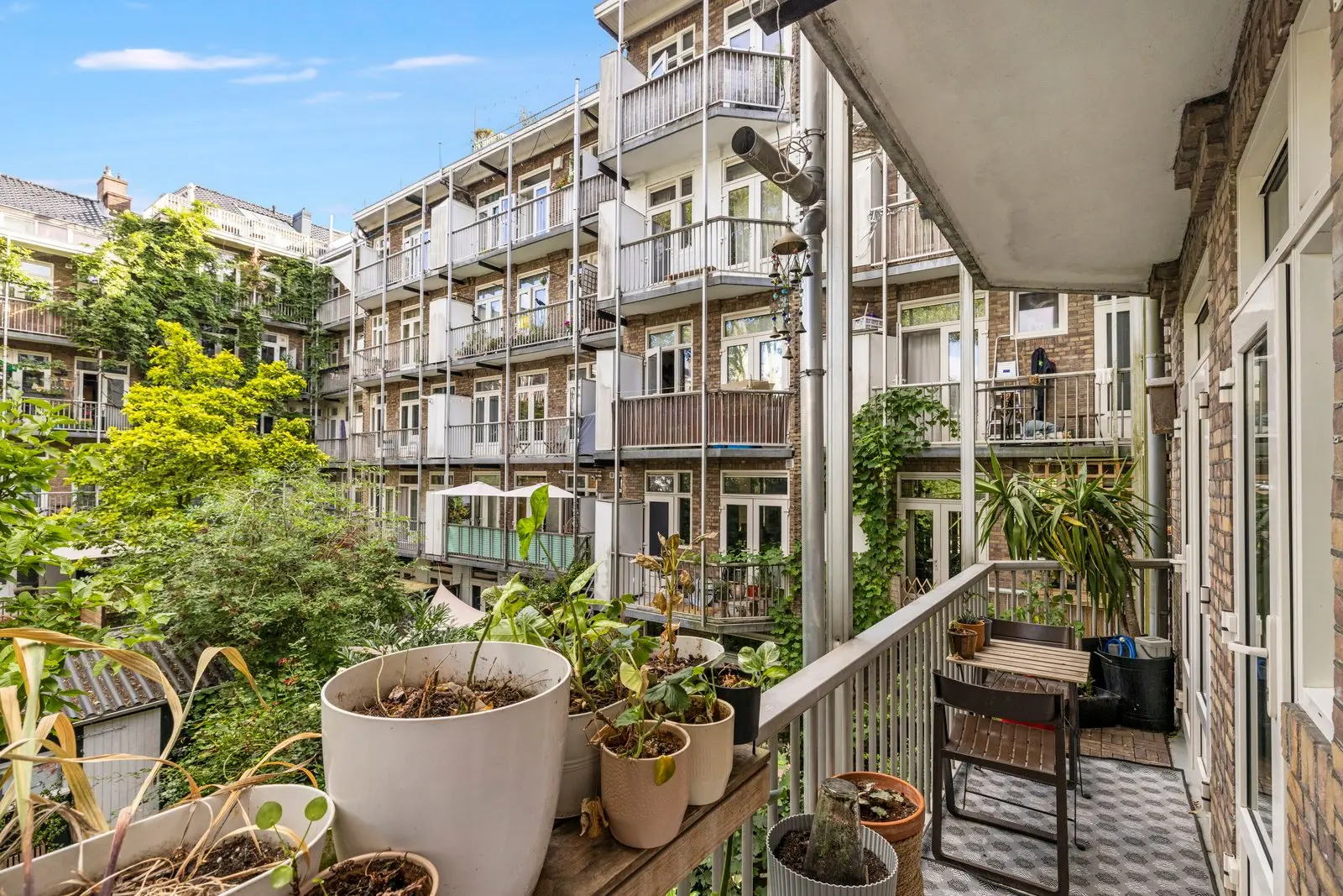 Balkon met planten en zicht op de galerijflat aan de overkant