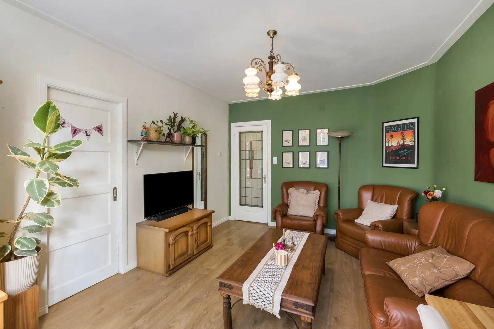 Woonkamer met groene wand, leren fauteuils en een schouw