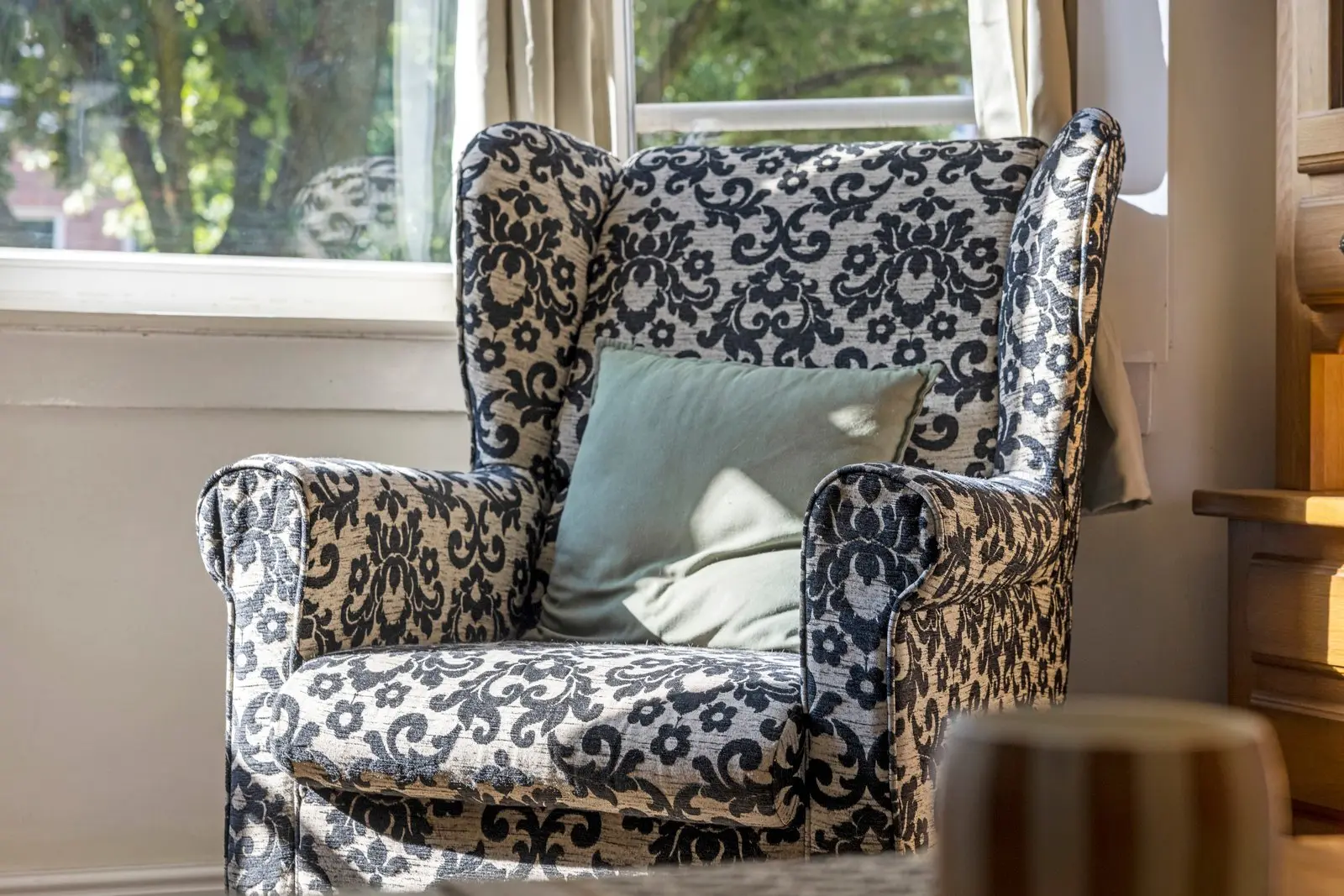 Gestoffeerde oorfauteuil in het licht van de erker