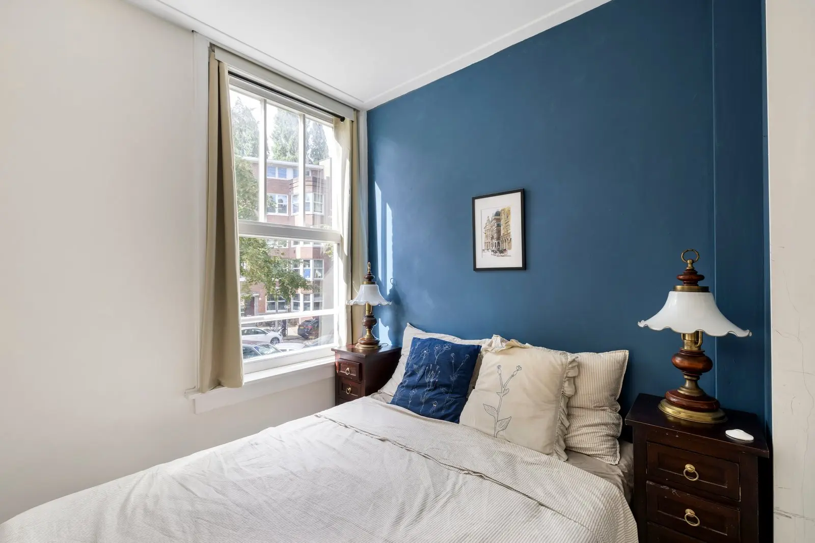 Slaapkamer met blauwe wand en twee ramen op de straat