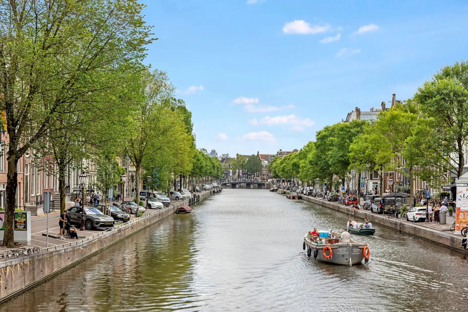 Gracht met boten op het water, bomen en geparkeerde auto's langs beide kades