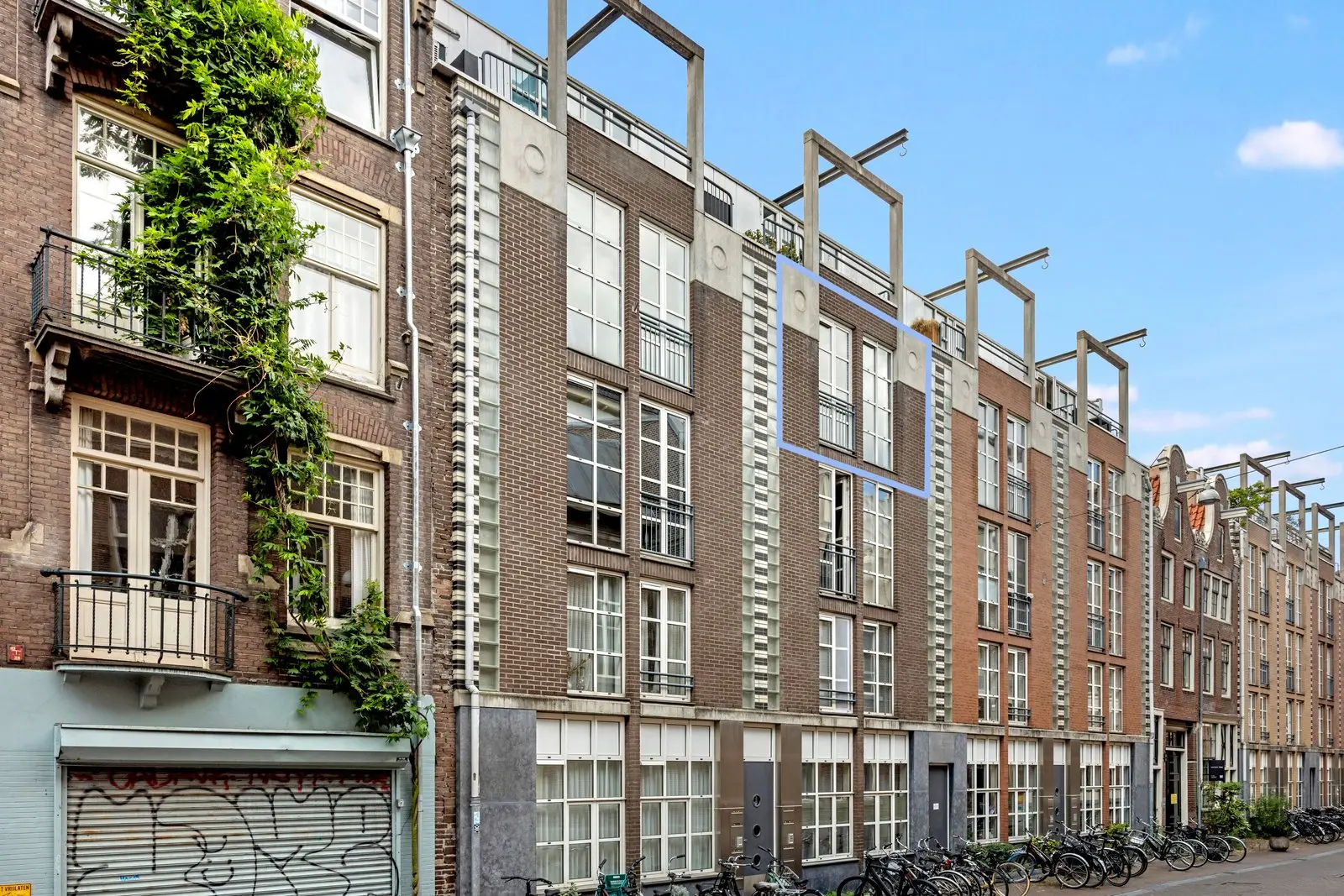 Blauw kader om de ramen van de woning in de bakstenen gevel, met fietsen langs de stoep