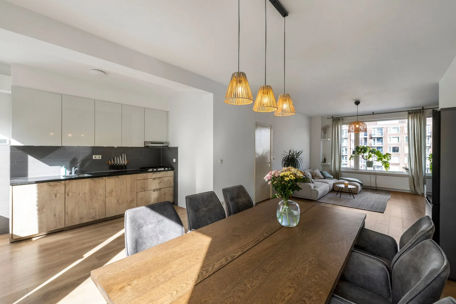 Open woonruimte met het keukenblok, de eettafel en de zithoek bij het raam