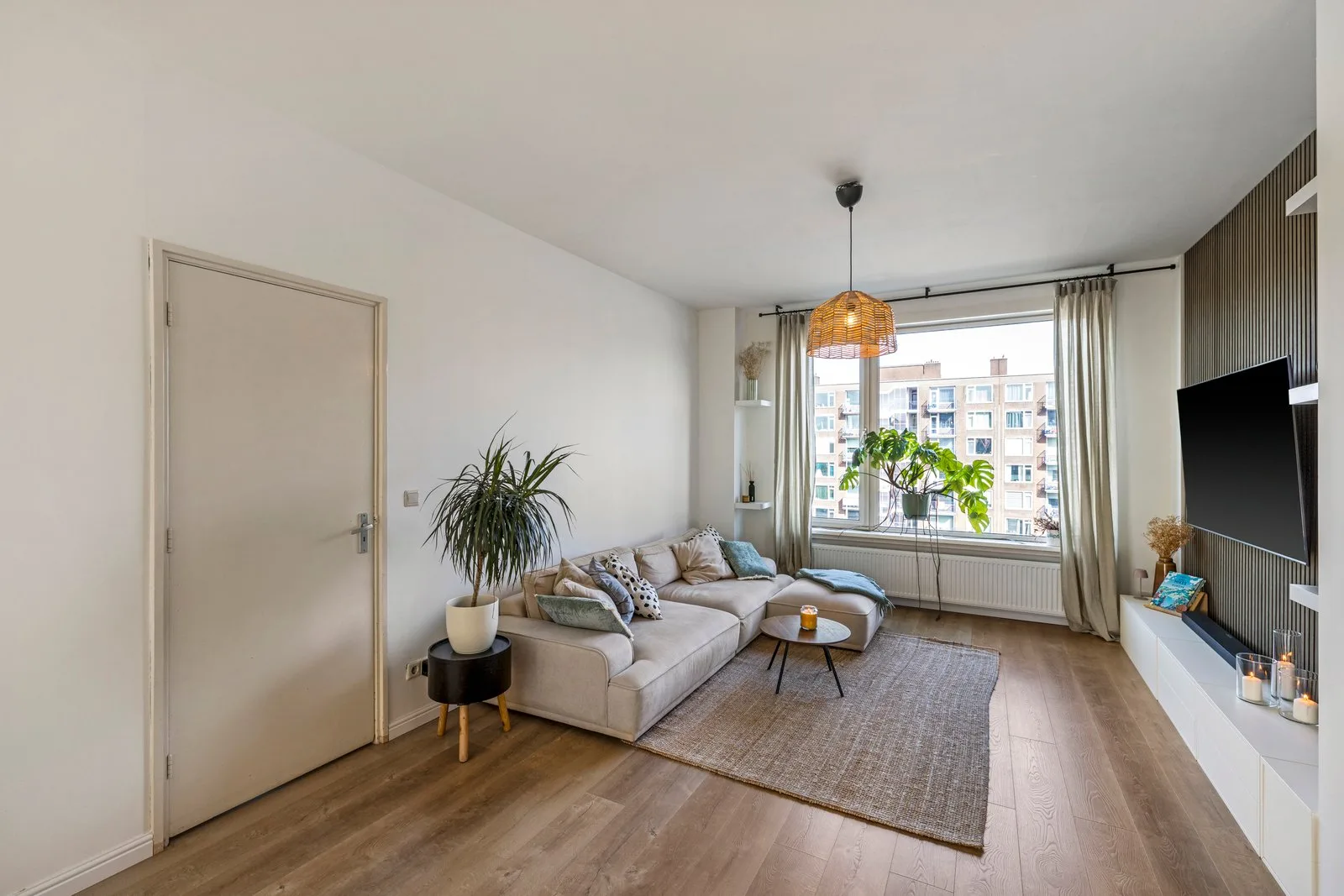 Zithoek met beige hoekbank, een jute vloerkleed en daglicht door het raam
