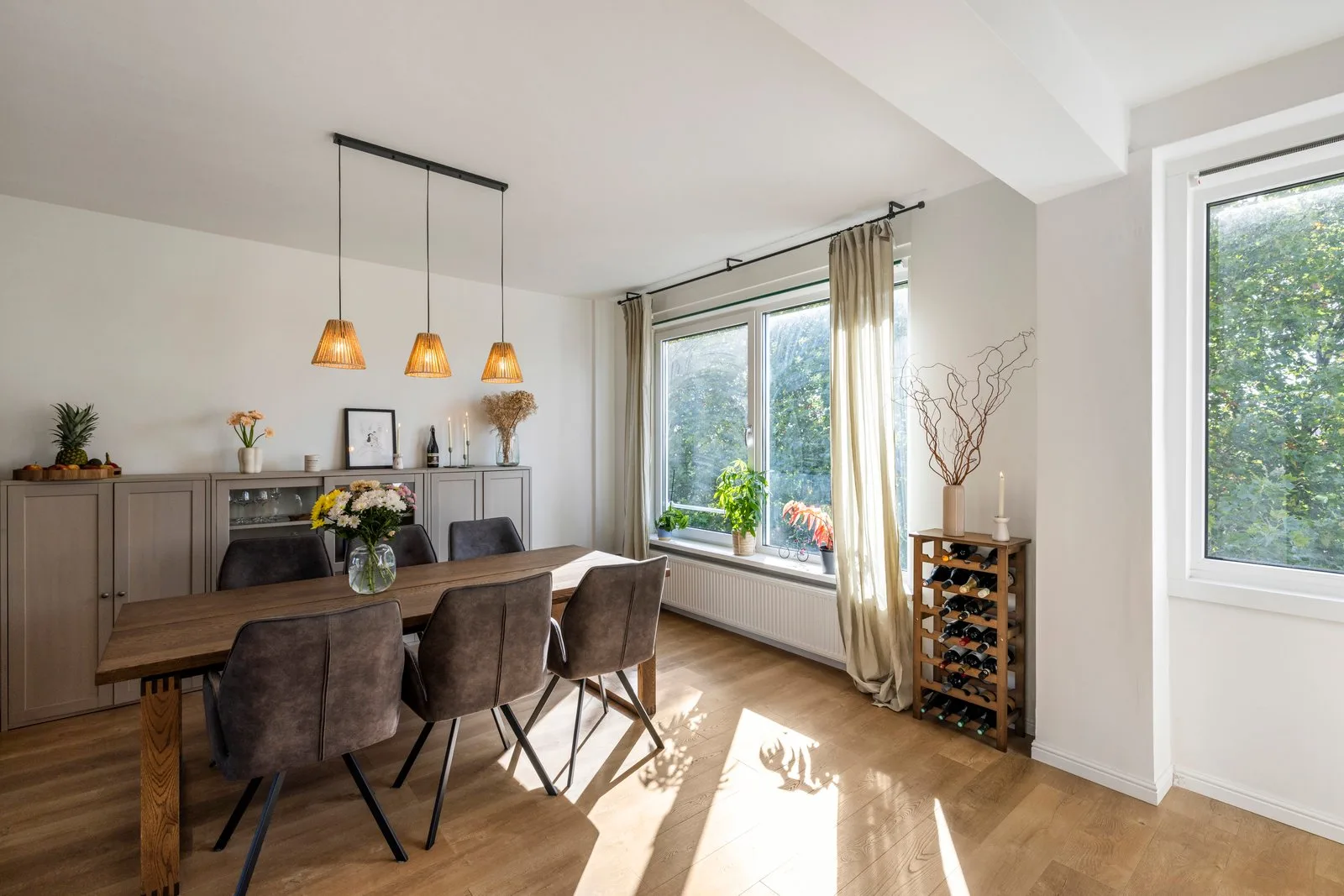 Eethoek met zes stoelen, een dressoirwand en het wijnrek bij het raam