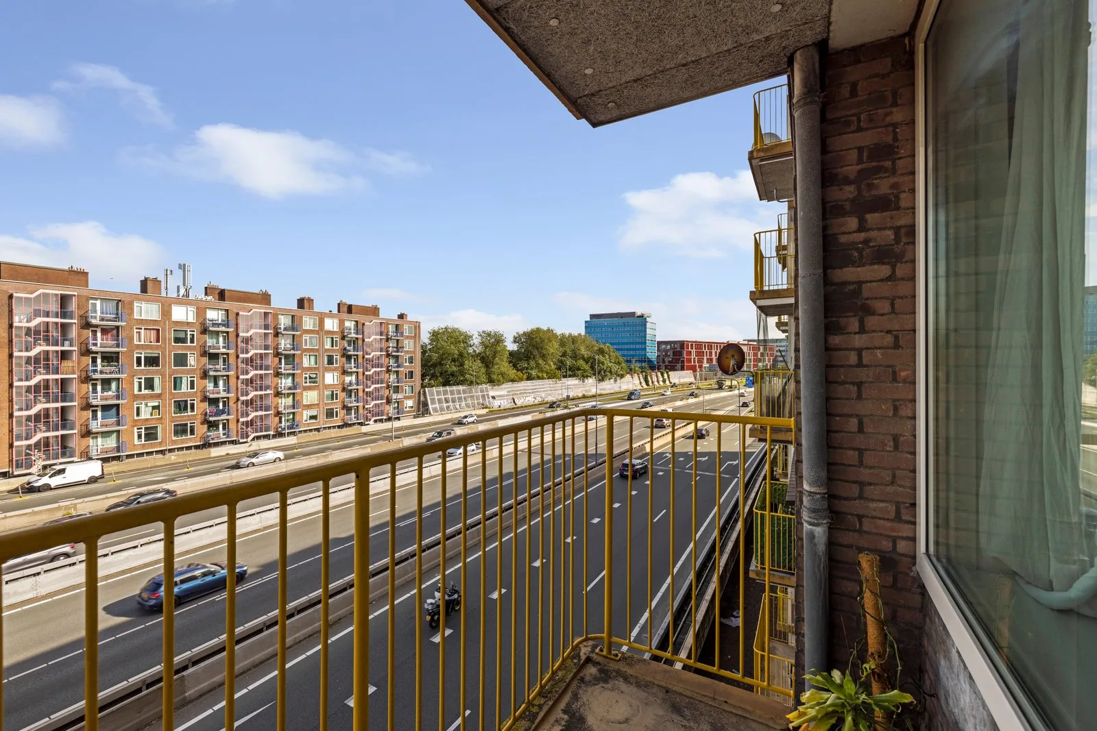 Zicht over de snelweg op het bakstenen woonblok aan de overkant