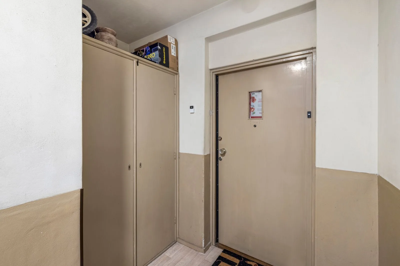 Voordeur van de woning in het gemeenschappelijke portaal, met bergkasten ernaast