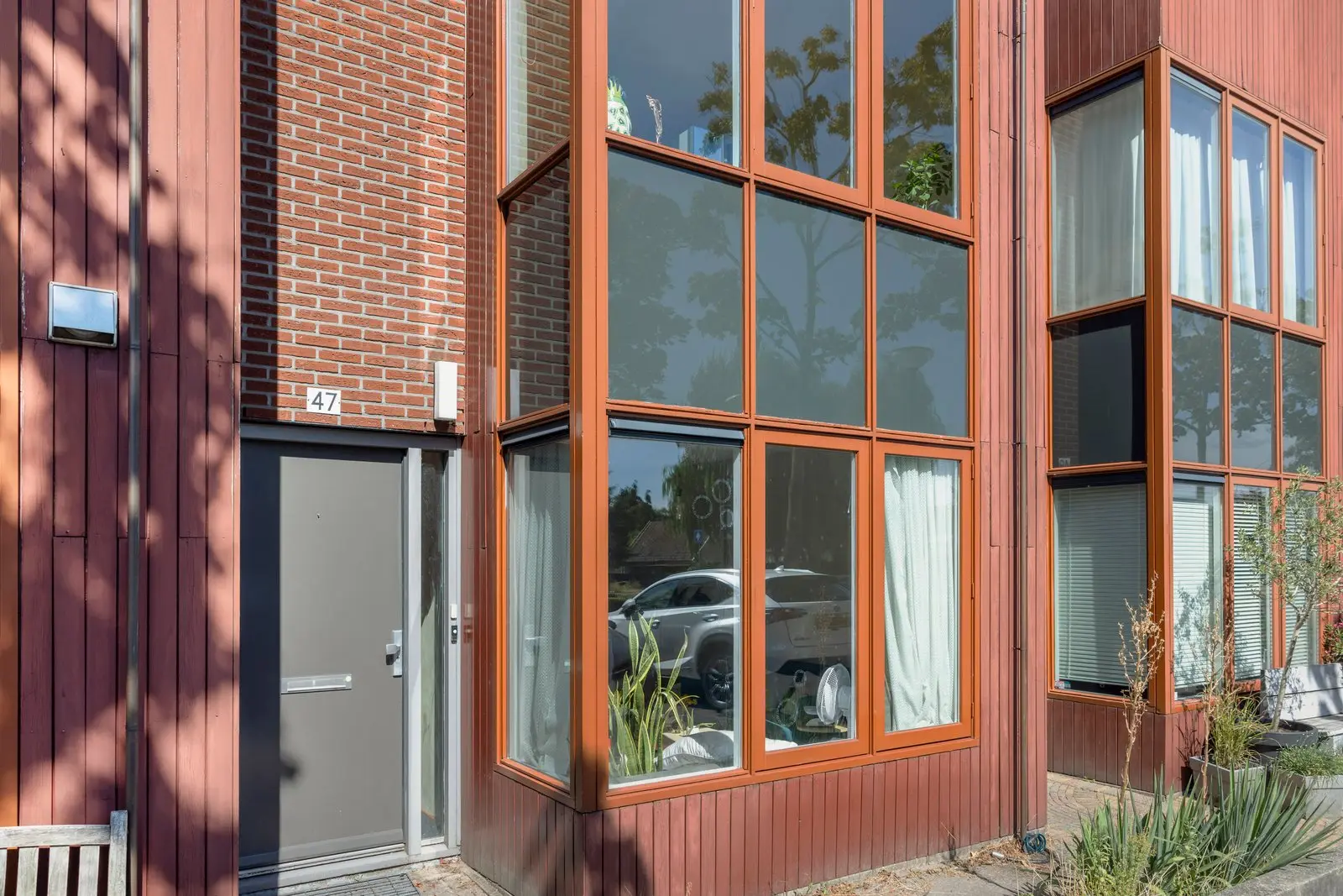 Detail van de houten kozijnen en de rode gevelbekleding