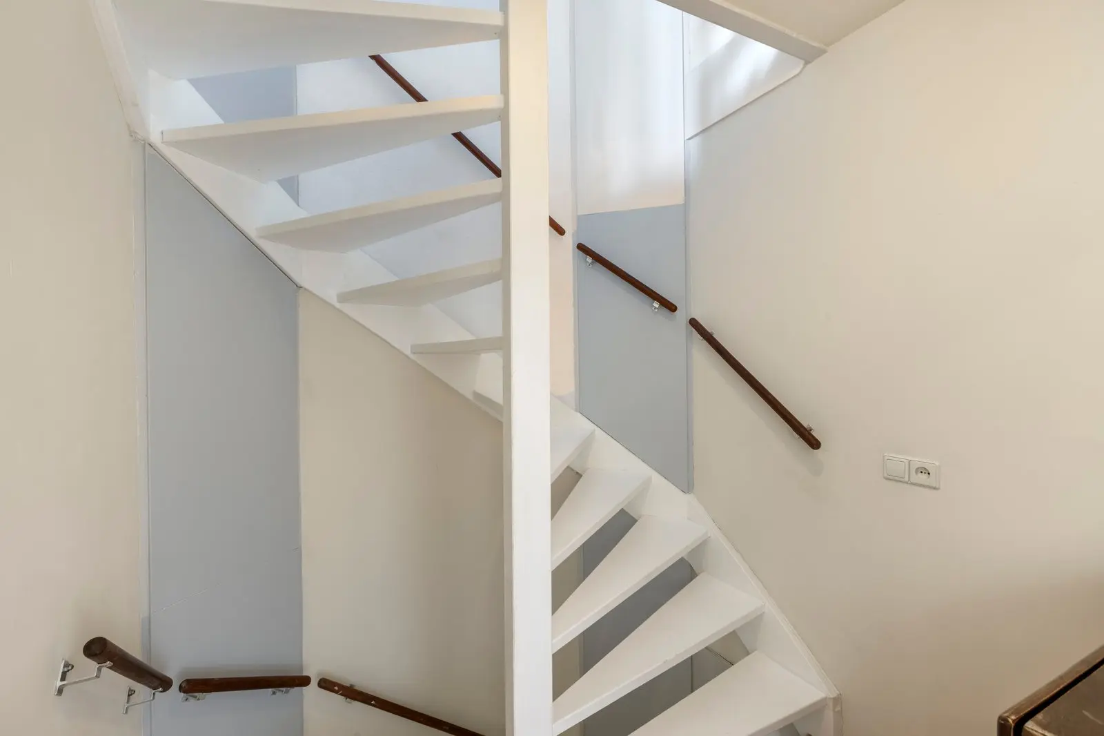 Wit trappenhuis met houten leuning