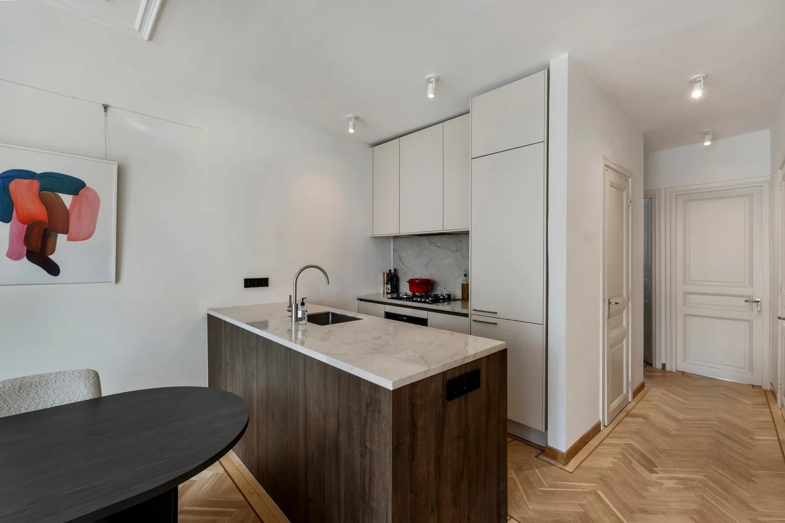 De keuken heeft een marmeren blad, donkerhouten spoeleiland en witte kastenwand tot het plafond