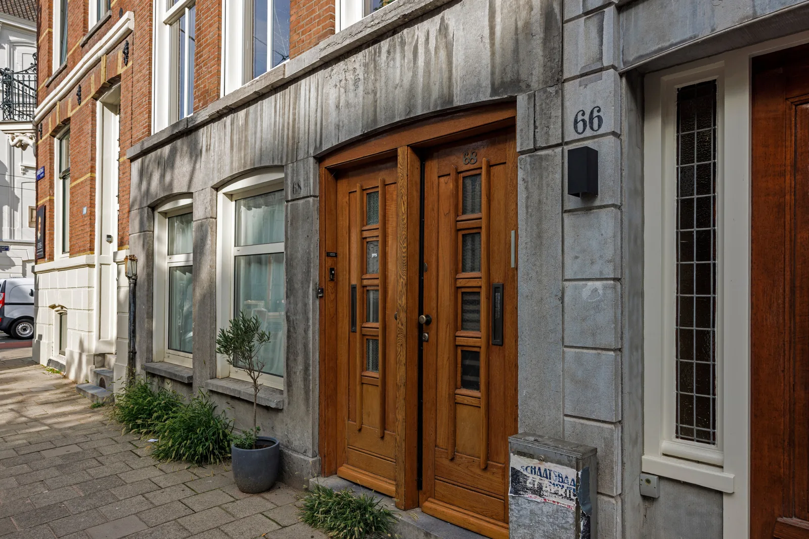 Eiken dubbele voordeur met glasstroken in een natuurstenen omlijsting, ernaast een olijfboompje