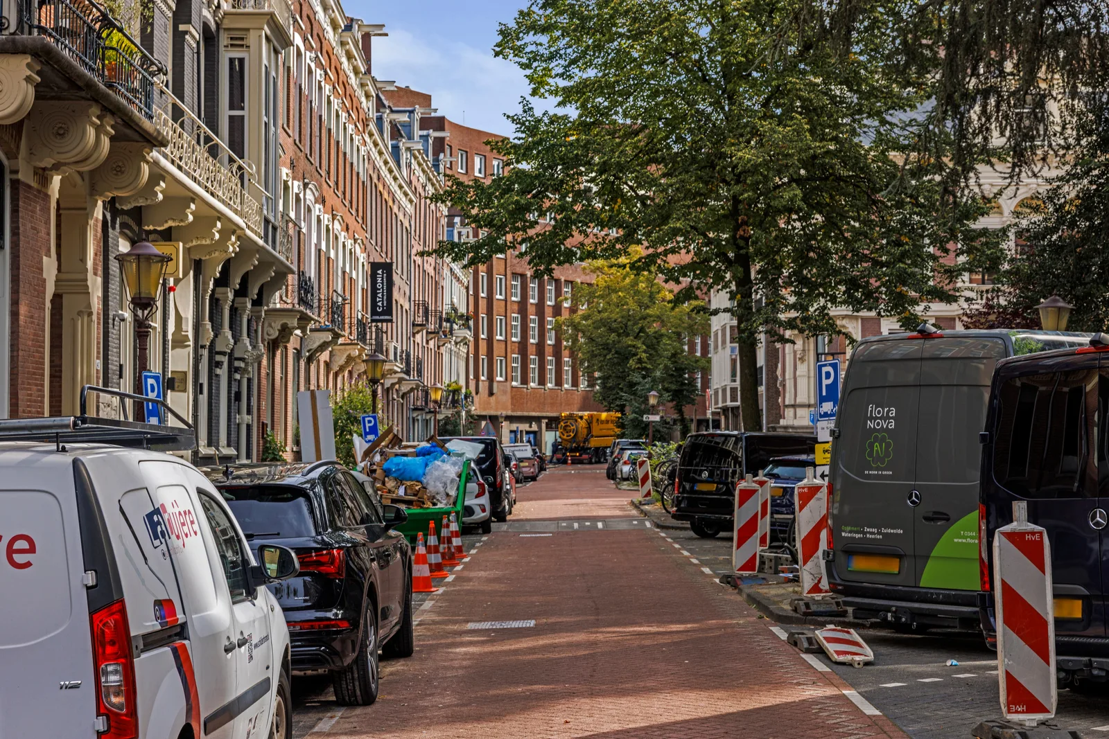 Geparkeerde auto's in een smalle straat, negentiende-eeuwse gevels met balkons en gietijzeren hekwerk