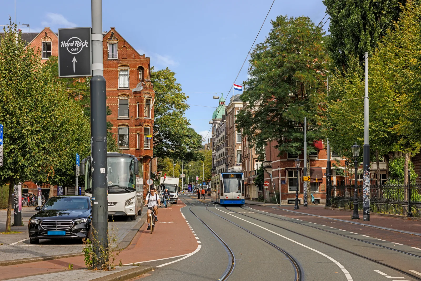 Tram 24 rijdt over de rails, op het rode fietspad passeert een fietser