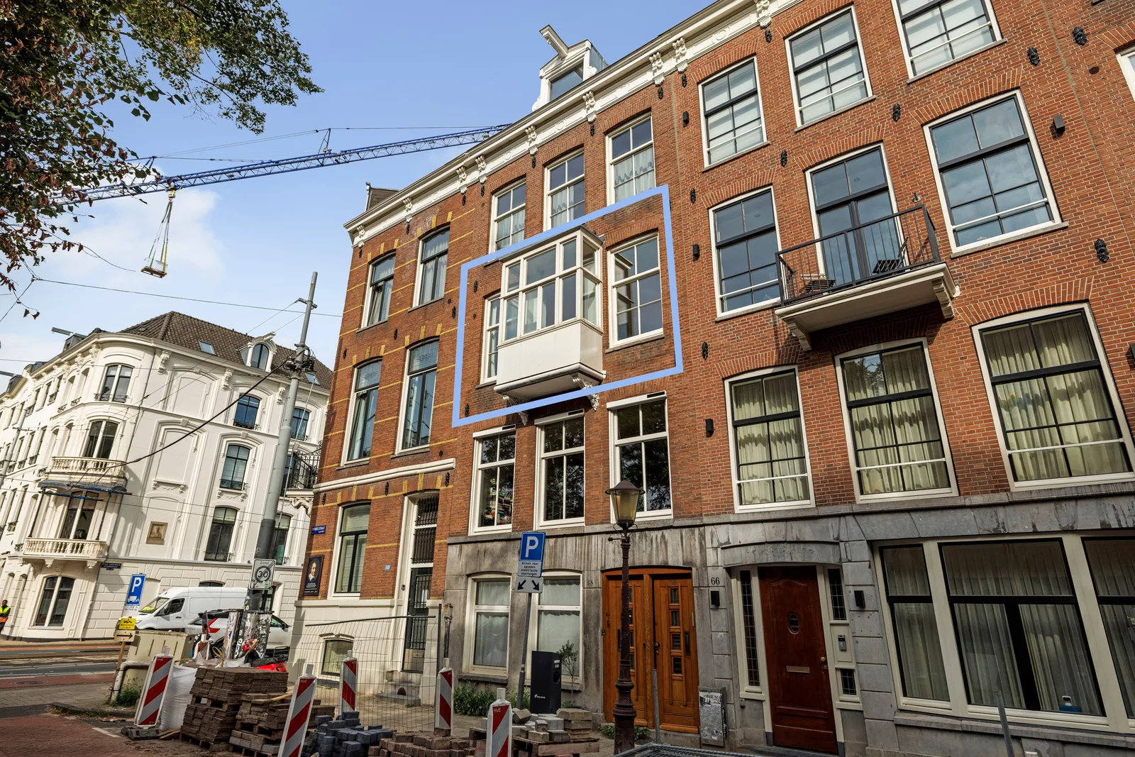 Blauw kader om de erker in de bakstenen voorgevel, beneden de houten voordeuren