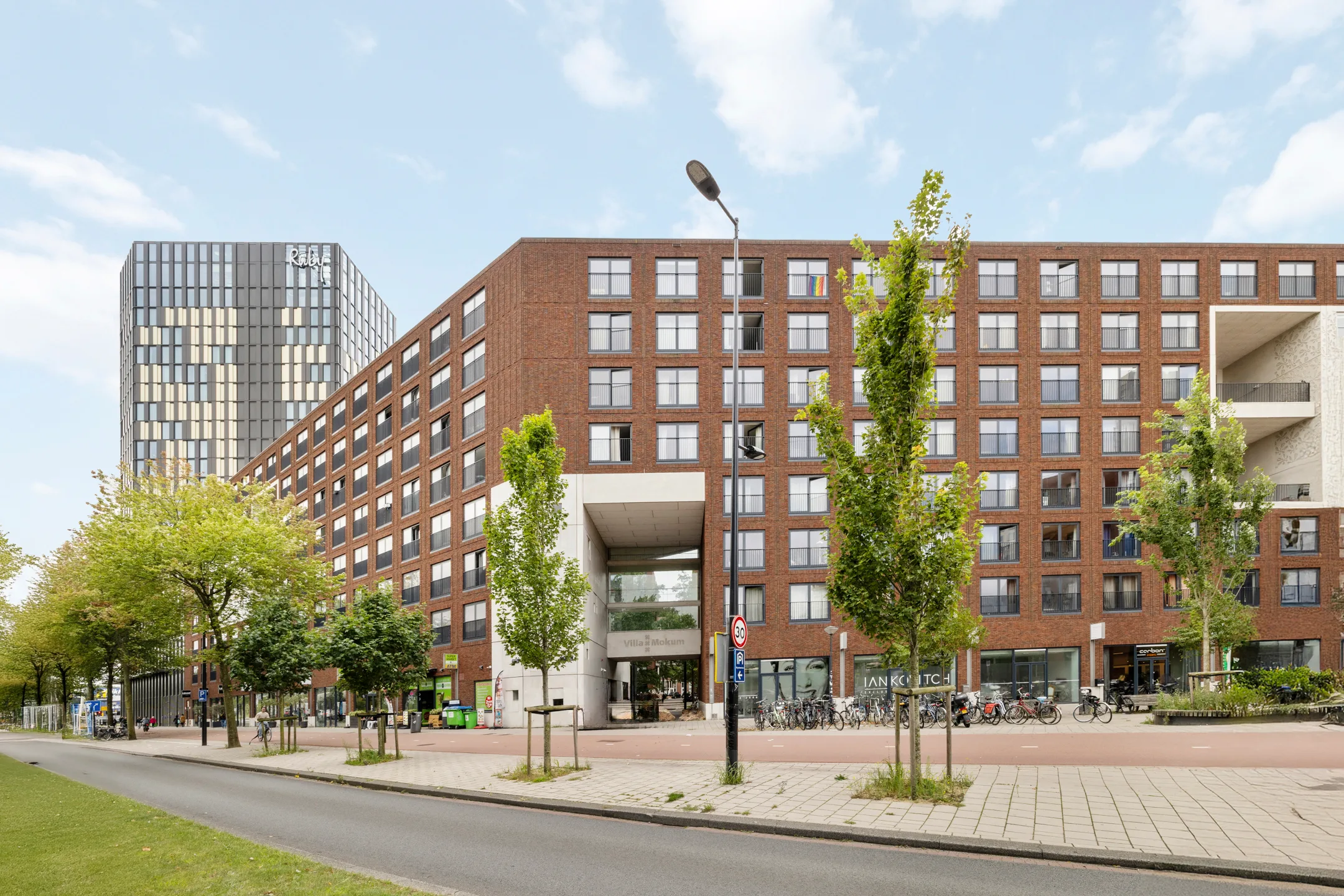 Het wooncomplex vanaf de straat, met de overdekte doorgang en winkels op de begane grond