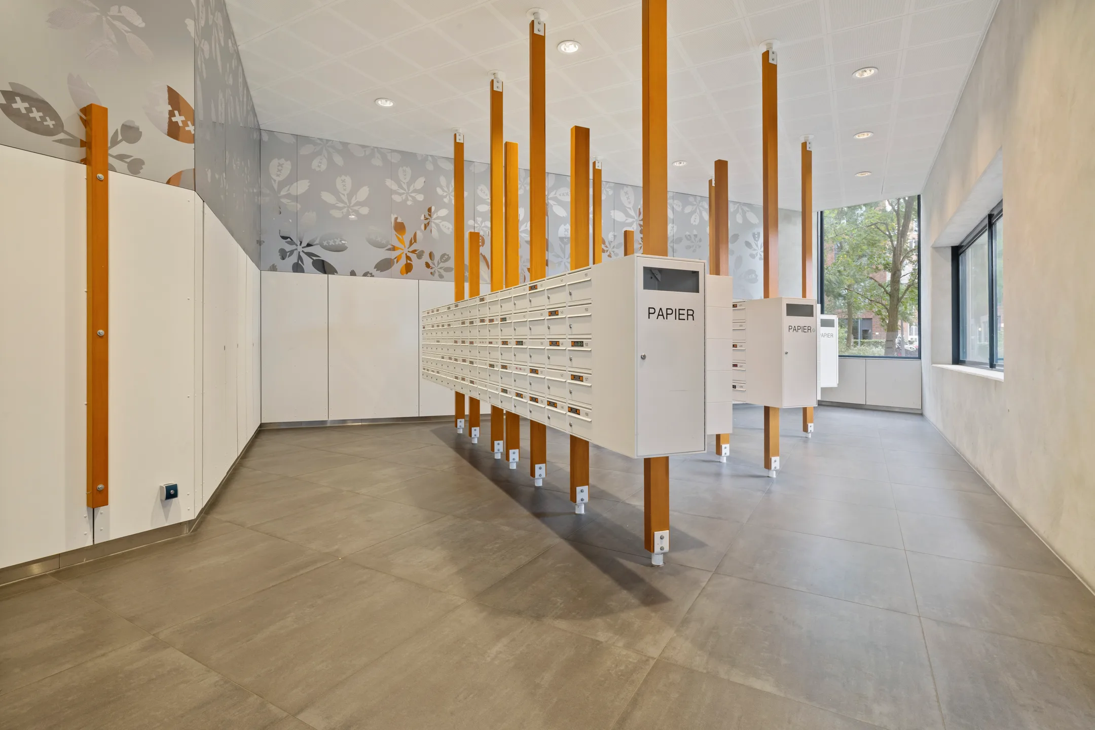 Gemeenschappelijke entreehal met de rij postkasten en een wandmotief met Amsterdamse kruisjes