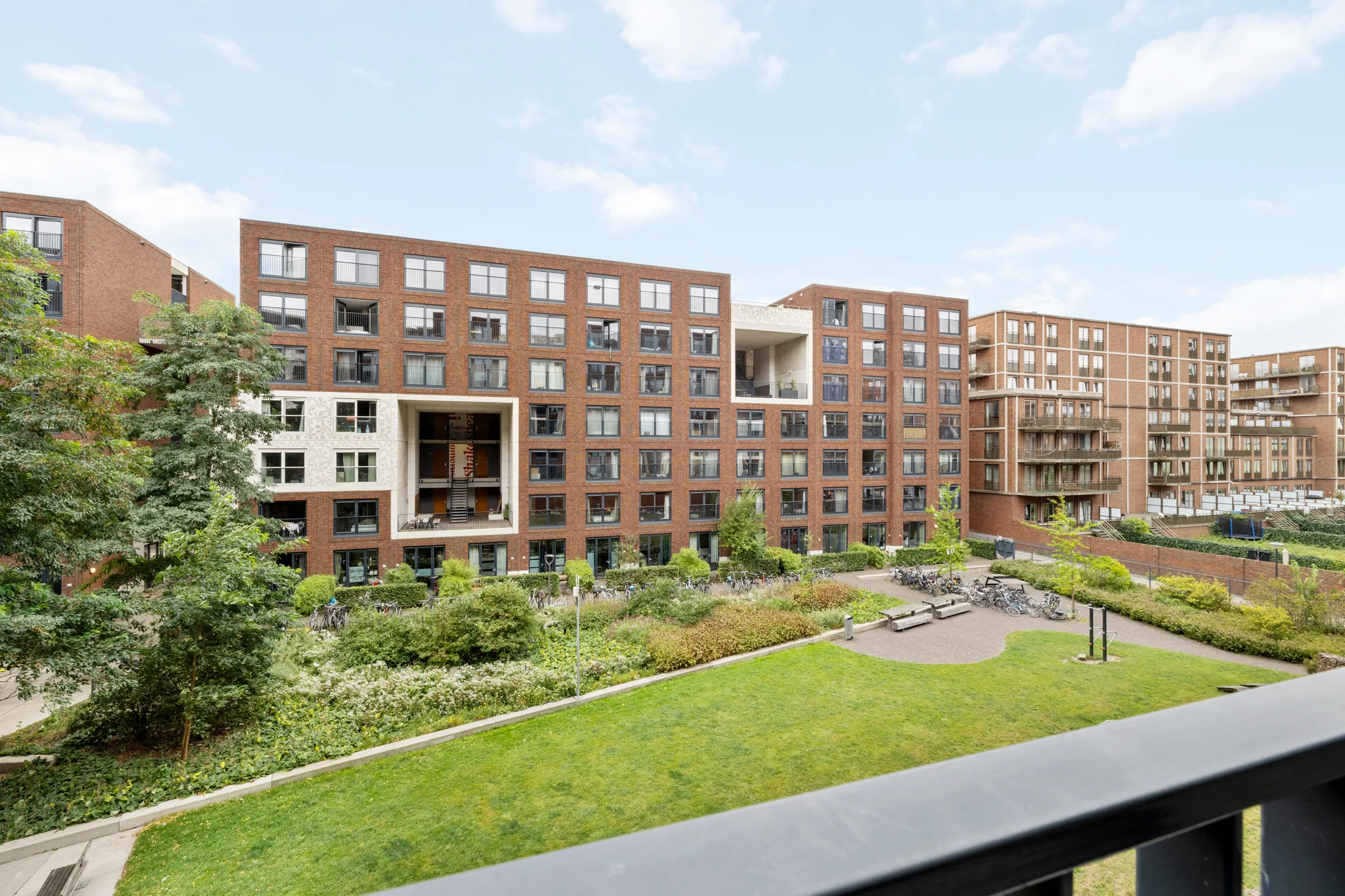 Uitzicht vanaf het balkon over het binnenhof, met het tegenoverliggende woonblok