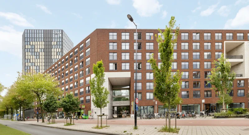 Bakstenen wooncomplex met huurappartementen en winkels op de begane grond in Amsterdam